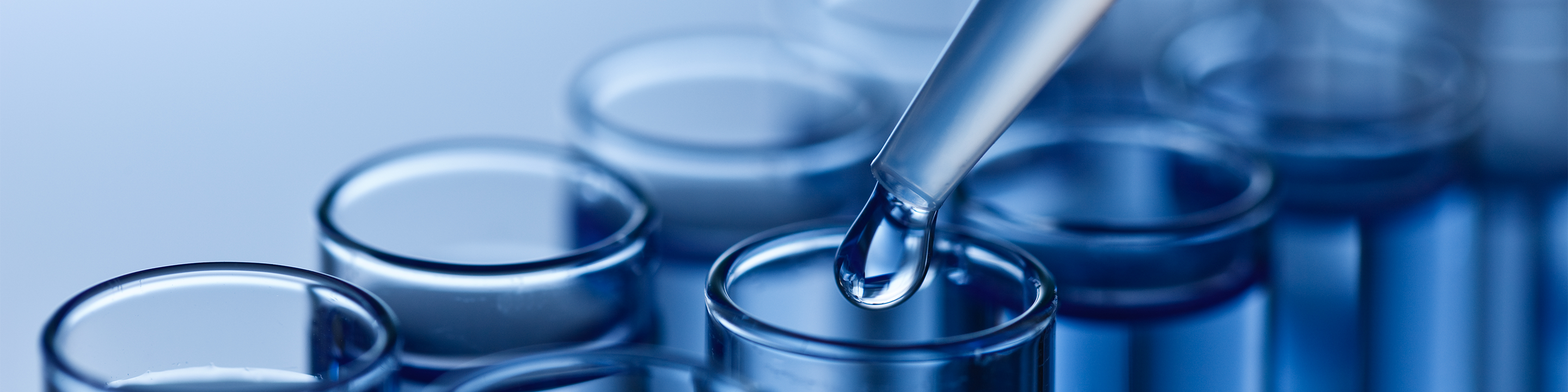 Series of test tubes with a pippette dripping liquid into one.